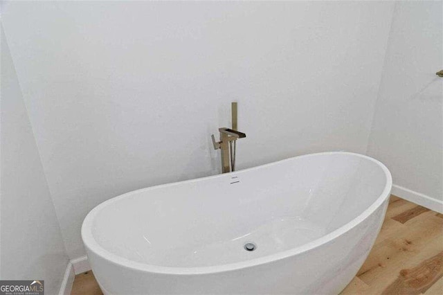 bathroom with a bathtub and hardwood / wood-style flooring