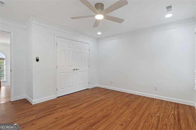 unfurnished bedroom featuring ornamental molding, a closet, hardwood / wood-style flooring, and ceiling fan