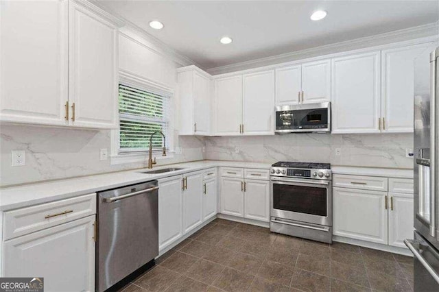 kitchen with sink, appliances with stainless steel finishes, ornamental molding, tasteful backsplash, and white cabinets