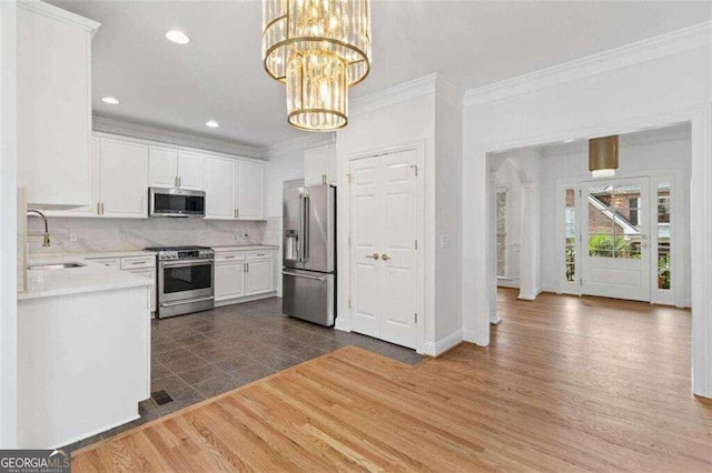 kitchen featuring hanging light fixtures, sink, dark hardwood / wood-style floors, white cabinetry, and appliances with stainless steel finishes