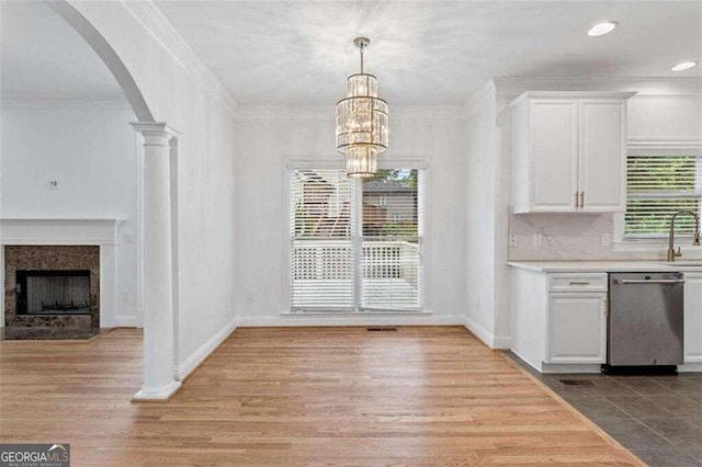 unfurnished dining area with ornate columns, a wealth of natural light, light hardwood / wood-style floors, and crown molding