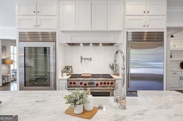 885 Crabapple Hl, Milton, GA 30004 - kitchen featuring high quality appliances, light stone countertops, white cabinets, decorative backsplash, and custom exhaust hood
