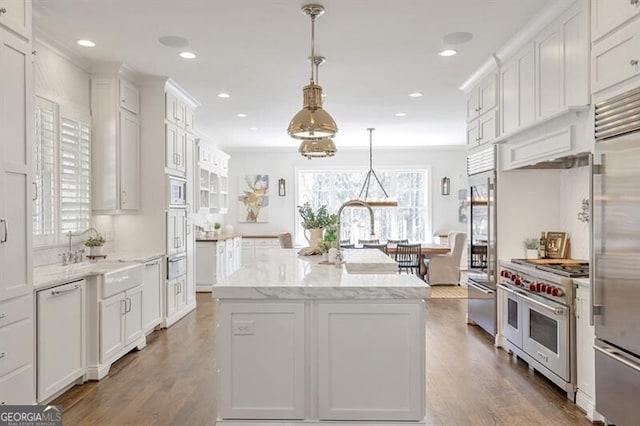 885 Crabapple Hl, Milton, GA 30004 - kitchen with sink, white cabinets, hanging light fixtures, built in appliances, and a center island with sink