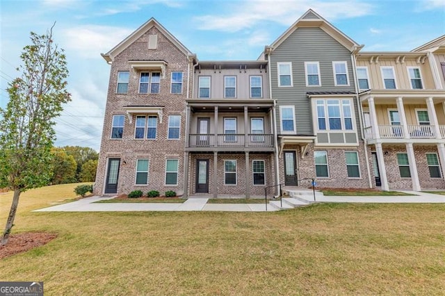 townhome / multi-family property featuring a balcony and a front yard