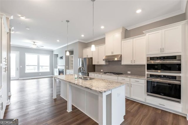 kitchen featuring stainless steel appliances, hanging light fixtures, sink, white cabinets, and a kitchen island with sink