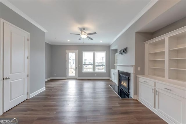 unfurnished living room featuring ornamental molding, dark hardwood / wood-style flooring, ceiling fan, and a high end fireplace