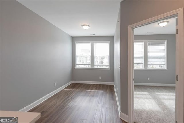 empty room featuring dark wood-type flooring and plenty of natural light