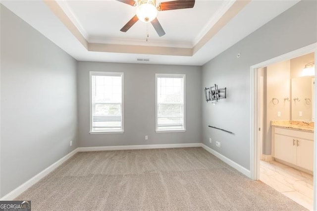 carpeted empty room with ceiling fan, crown molding, and a tray ceiling