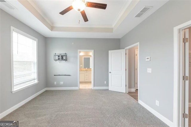 unfurnished bedroom featuring ensuite bathroom, carpet, ceiling fan, a raised ceiling, and crown molding