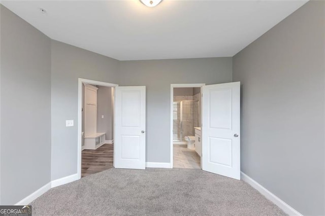 unfurnished bedroom with light carpet and connected bathroom