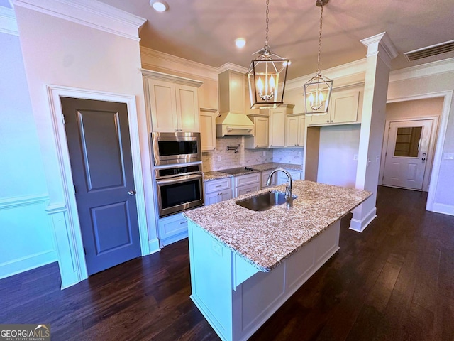 kitchen with premium range hood, pendant lighting, sink, a kitchen island with sink, and stainless steel appliances