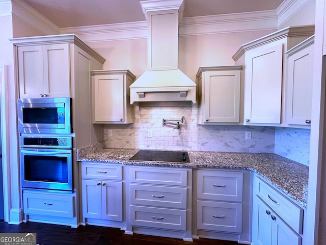 kitchen with premium range hood, appliances with stainless steel finishes, tasteful backsplash, white cabinetry, and ornamental molding