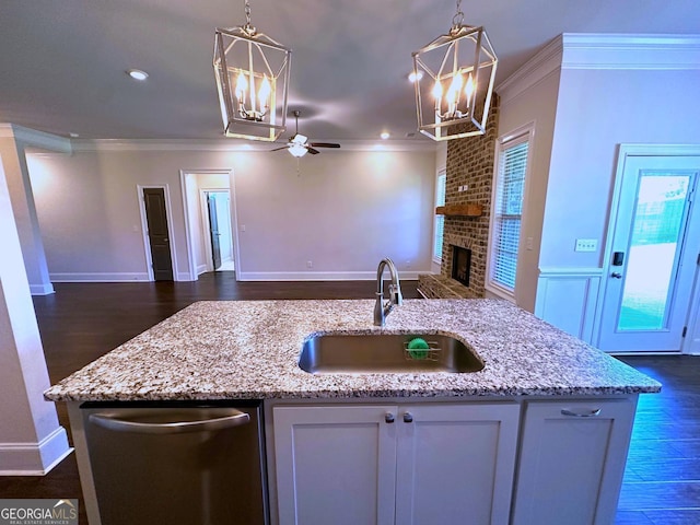 kitchen featuring a fireplace, decorative light fixtures, white cabinetry, dishwasher, and sink