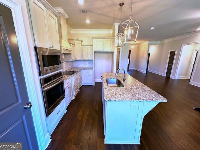 kitchen featuring sink, light stone counters, decorative light fixtures, a center island with sink, and stainless steel appliances