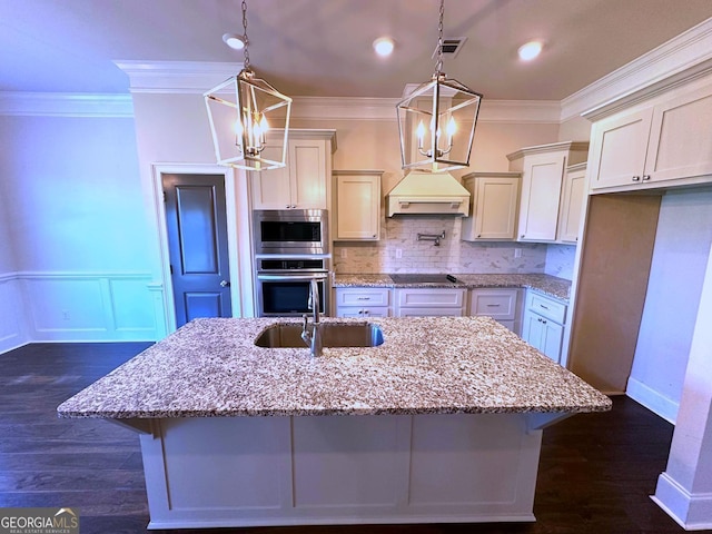 kitchen with sink, hanging light fixtures, stainless steel appliances, light stone counters, and custom range hood