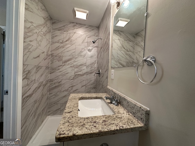 bathroom featuring tiled shower and vanity