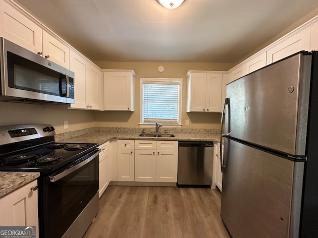 kitchen with white cabinets, sink, light wood-type flooring, and appliances with stainless steel finishes