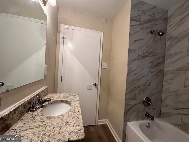 bathroom with tiled shower / bath combo, vanity, and wood-type flooring