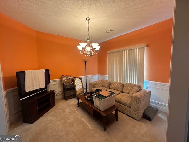 living room with light colored carpet, a textured ceiling, and an inviting chandelier