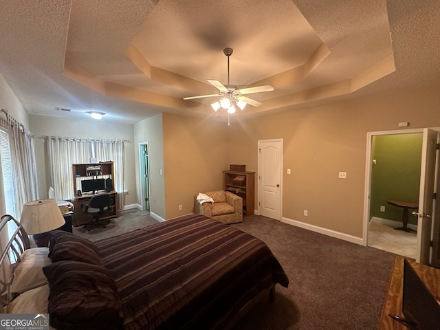 bedroom with ceiling fan, a textured ceiling, carpet flooring, and a tray ceiling