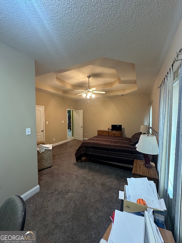 bedroom with ceiling fan, a textured ceiling, carpet floors, and a tray ceiling