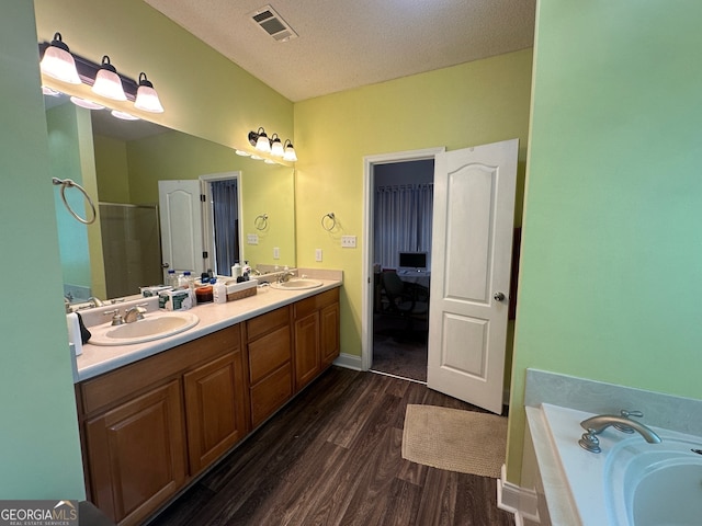 bathroom featuring plus walk in shower, wood-type flooring, vanity, and a textured ceiling