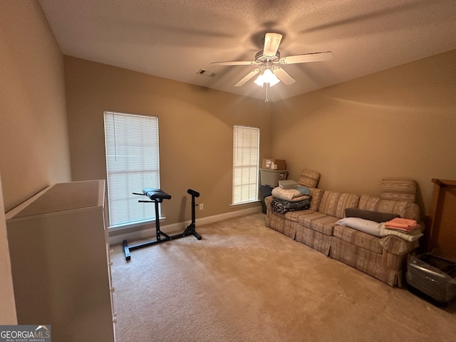 interior space featuring a textured ceiling, light colored carpet, and ceiling fan