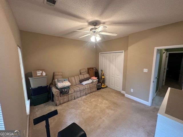 unfurnished room with a textured ceiling, light carpet, and ceiling fan