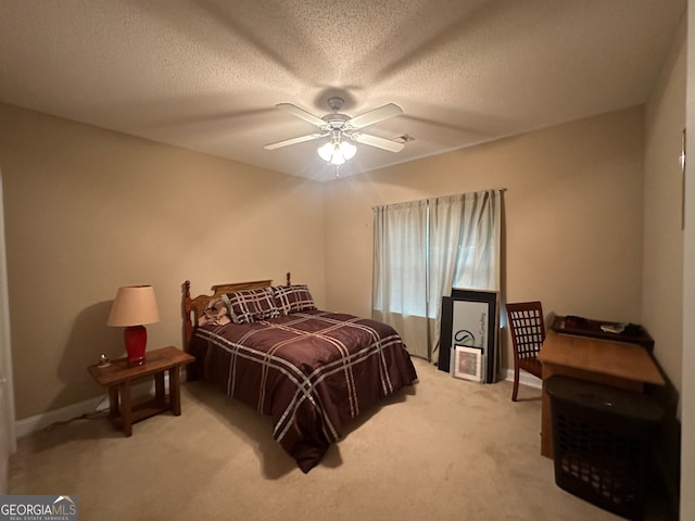 bedroom featuring a textured ceiling, light colored carpet, and ceiling fan