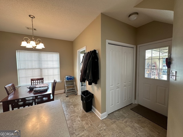 entrance foyer featuring a textured ceiling, an inviting chandelier, and vaulted ceiling