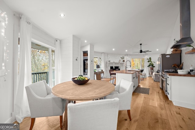 dining space with ceiling fan, plenty of natural light, a fireplace, and light hardwood / wood-style flooring