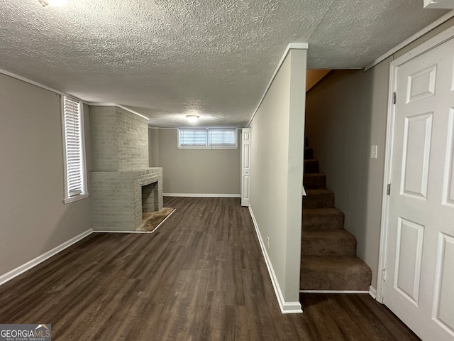 basement with a textured ceiling, a fireplace, and dark hardwood / wood-style floors