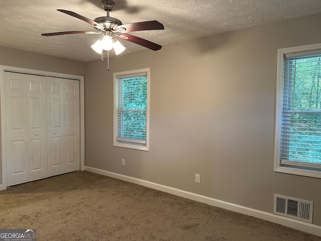 unfurnished bedroom featuring ceiling fan, a textured ceiling, a closet, and carpet floors