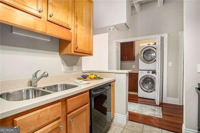 kitchen with light tile patterned flooring, stacked washer and clothes dryer, sink, and dishwasher