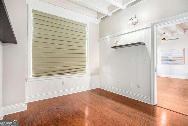 empty room with hardwood / wood-style flooring, ceiling fan, and beam ceiling