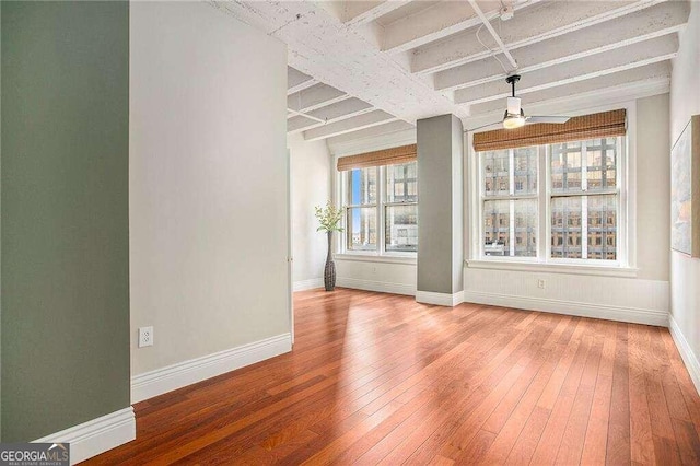 spare room featuring beamed ceiling, hardwood / wood-style flooring, and ceiling fan