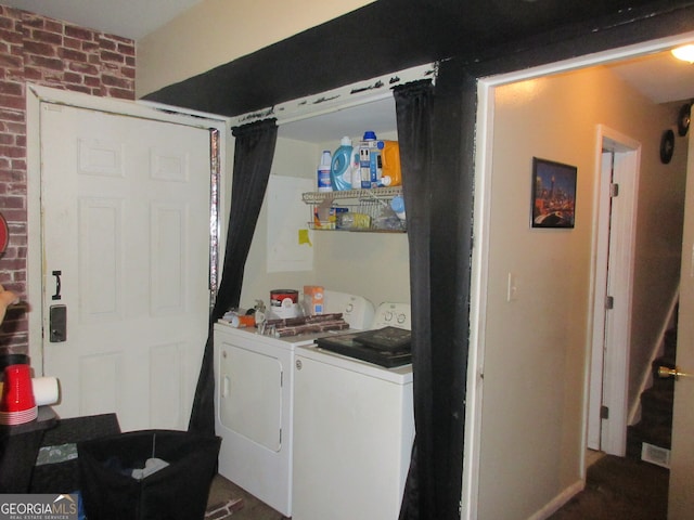 laundry area featuring separate washer and dryer and brick wall