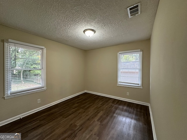 spare room featuring dark hardwood / wood-style flooring and a textured ceiling