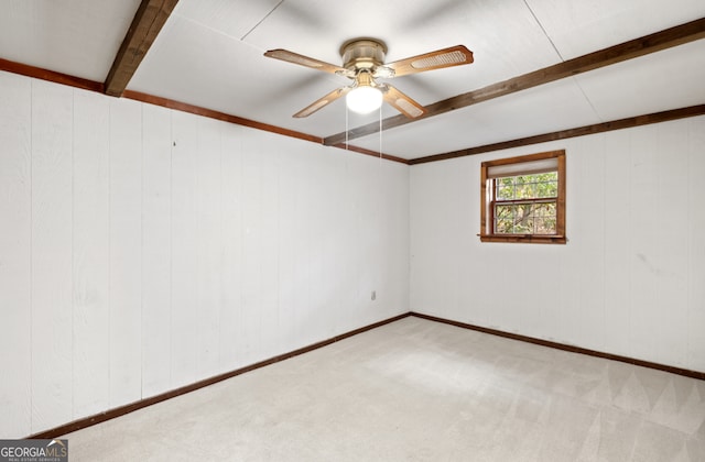 empty room featuring wood walls, light carpet, ceiling fan, and beam ceiling