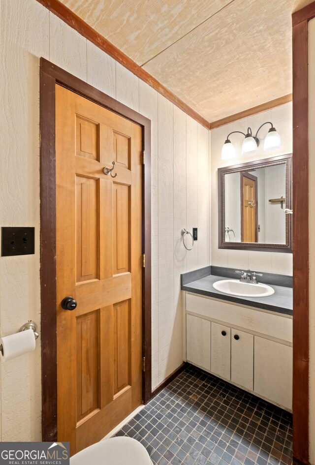 bathroom featuring vanity, wooden walls, a textured ceiling, and ornamental molding