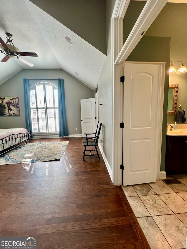 bedroom featuring sink, ceiling fan, a textured ceiling, light hardwood / wood-style flooring, and lofted ceiling