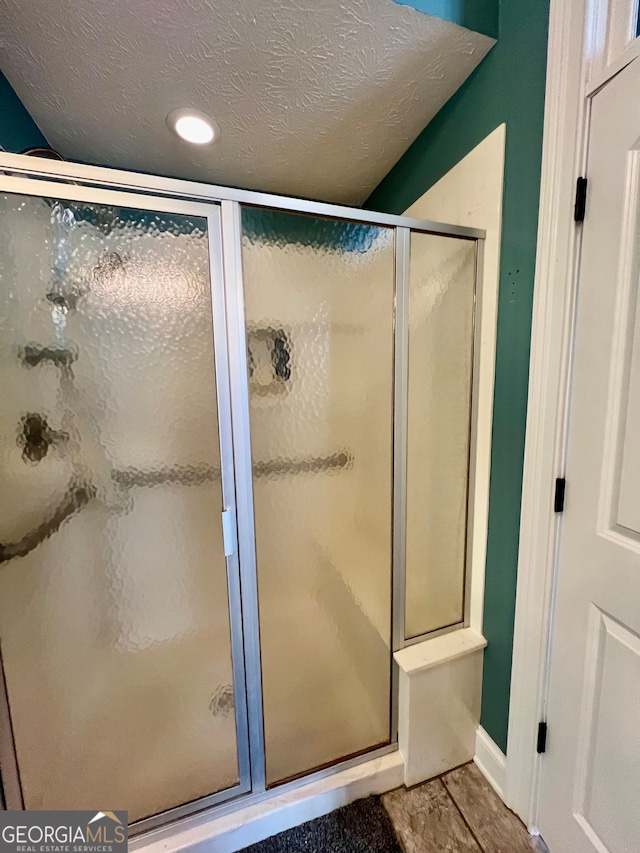 bathroom with tile patterned flooring, a textured ceiling, and a shower with shower door