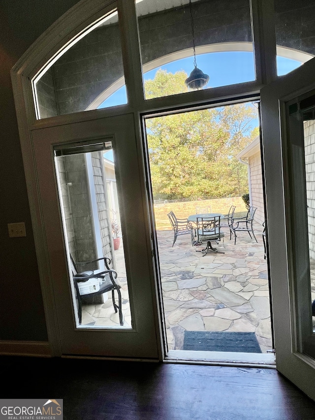 doorway to outside featuring wood-type flooring and vaulted ceiling