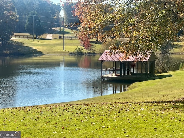 dock area with a water view and a lawn