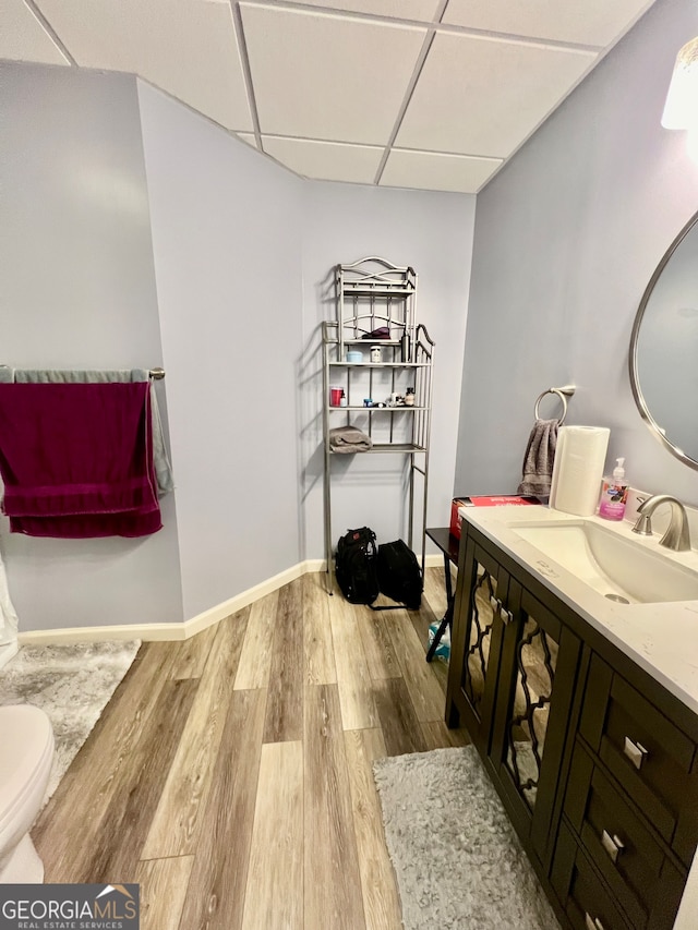 bathroom featuring toilet, a paneled ceiling, vanity, and hardwood / wood-style floors