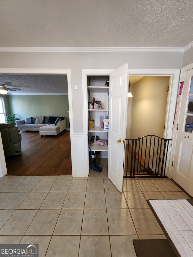 hall with a textured ceiling, light hardwood / wood-style flooring, and crown molding