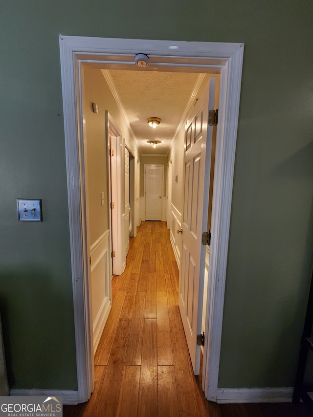 corridor with light hardwood / wood-style flooring and crown molding