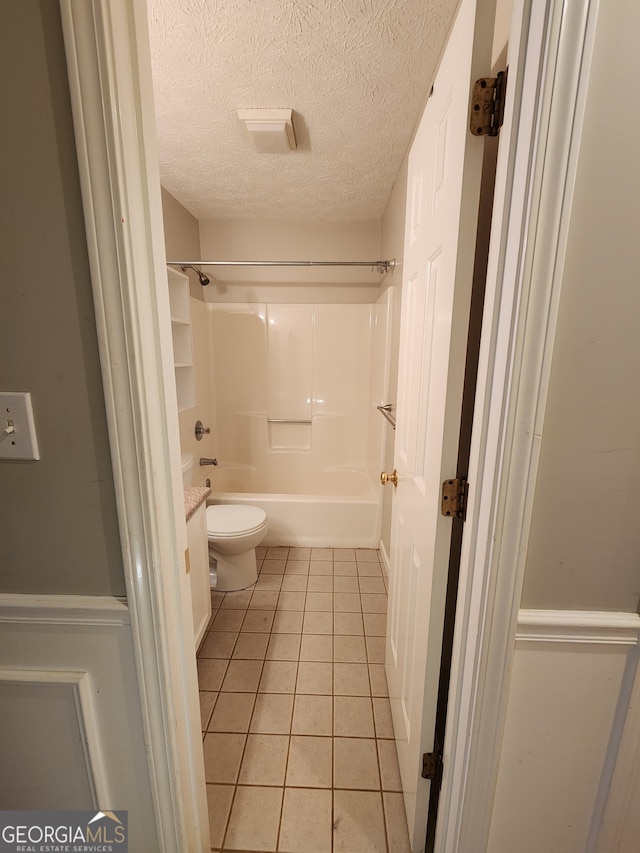 bathroom with tile patterned flooring, washtub / shower combination, a textured ceiling, and toilet