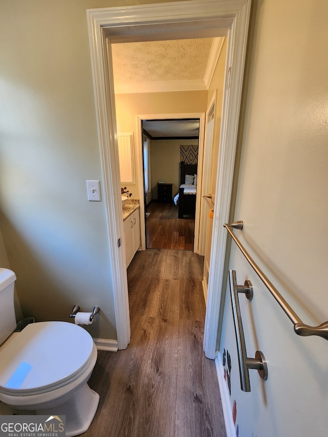 bathroom featuring vanity, toilet, wood-type flooring, and a textured ceiling