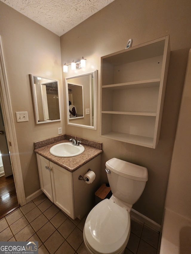 bathroom featuring vanity, a textured ceiling, tile patterned floors, and toilet